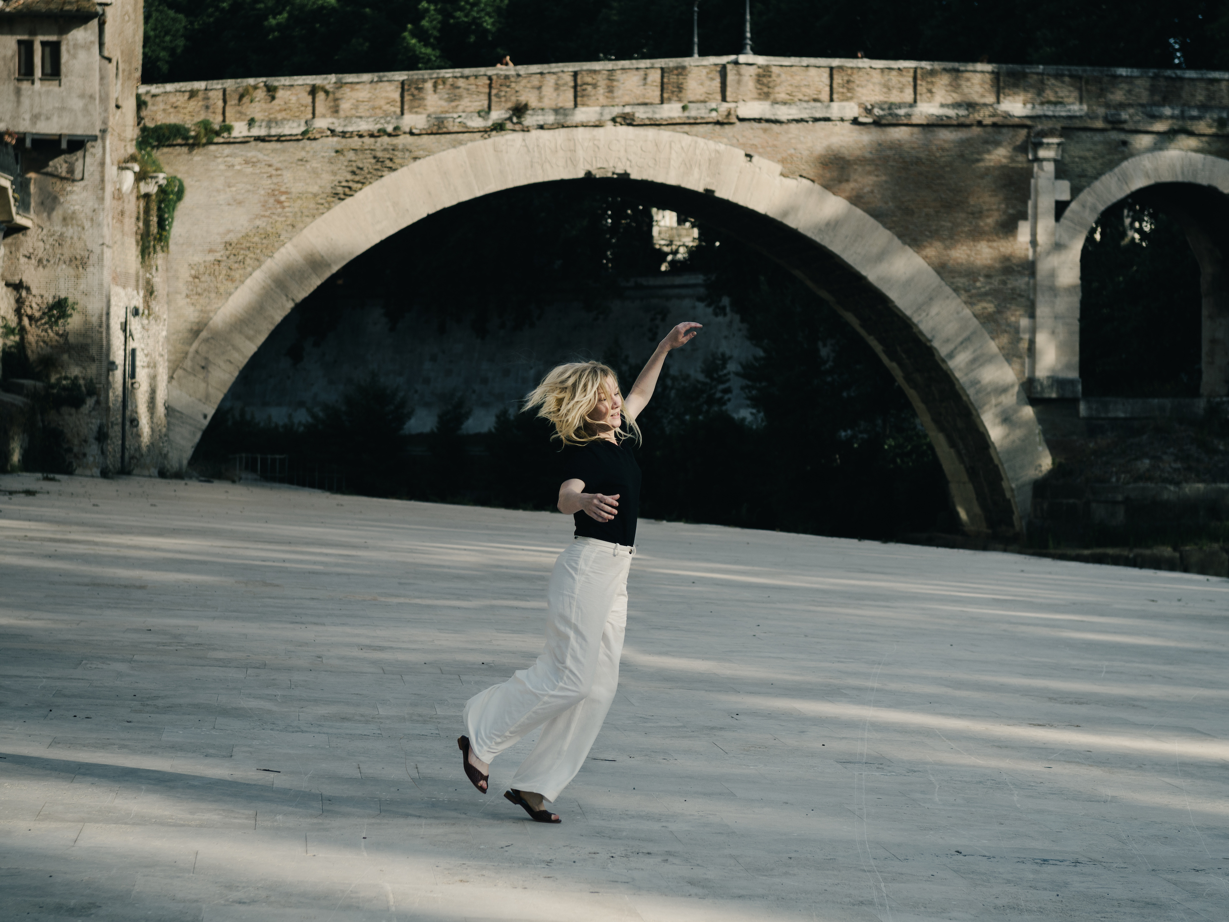 Ingeborg Bachmann (Sandra Hüller) hört Musik und tanzt unbeschwingt dazu am Ufer des Tibers in Rom.