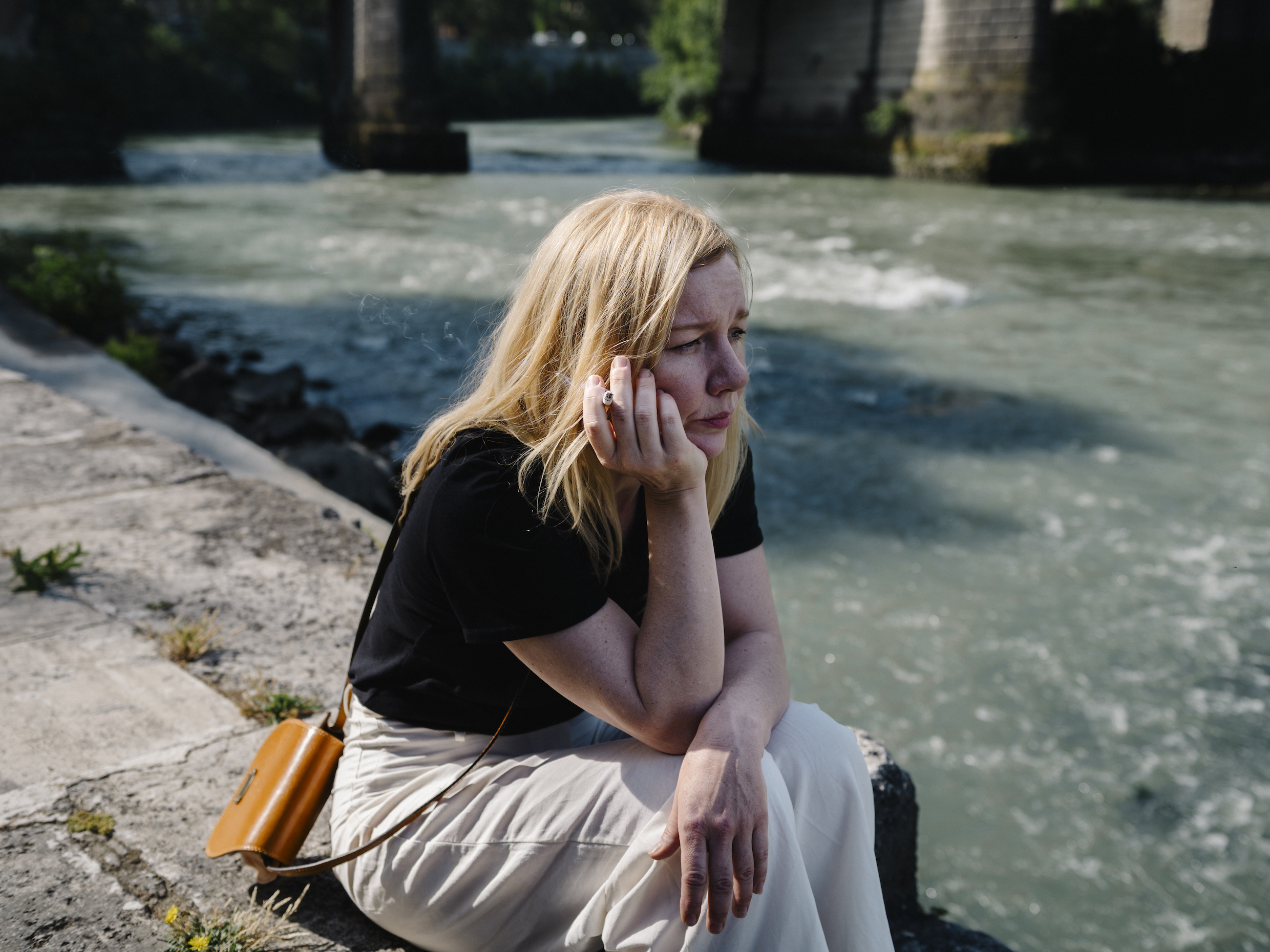 Ingeborg Bachmann (Sandra Hüller) sitzt, nachdenklich auf das Wasser schauend und rauchend, am Ufer des Tiber in Rom.